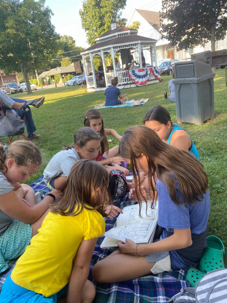 Kids in the park listening to music and looking at a picture book
